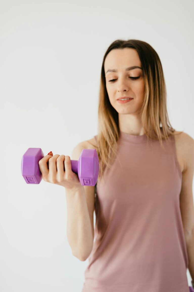 Strong young female athlete exercising with dumbbell